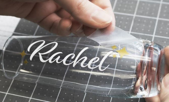 Clear plastic bottle with 'Rachael' printed on it, held by a hand against a grid background.