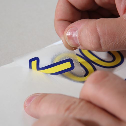 Person peeling a label with a logo off a surface