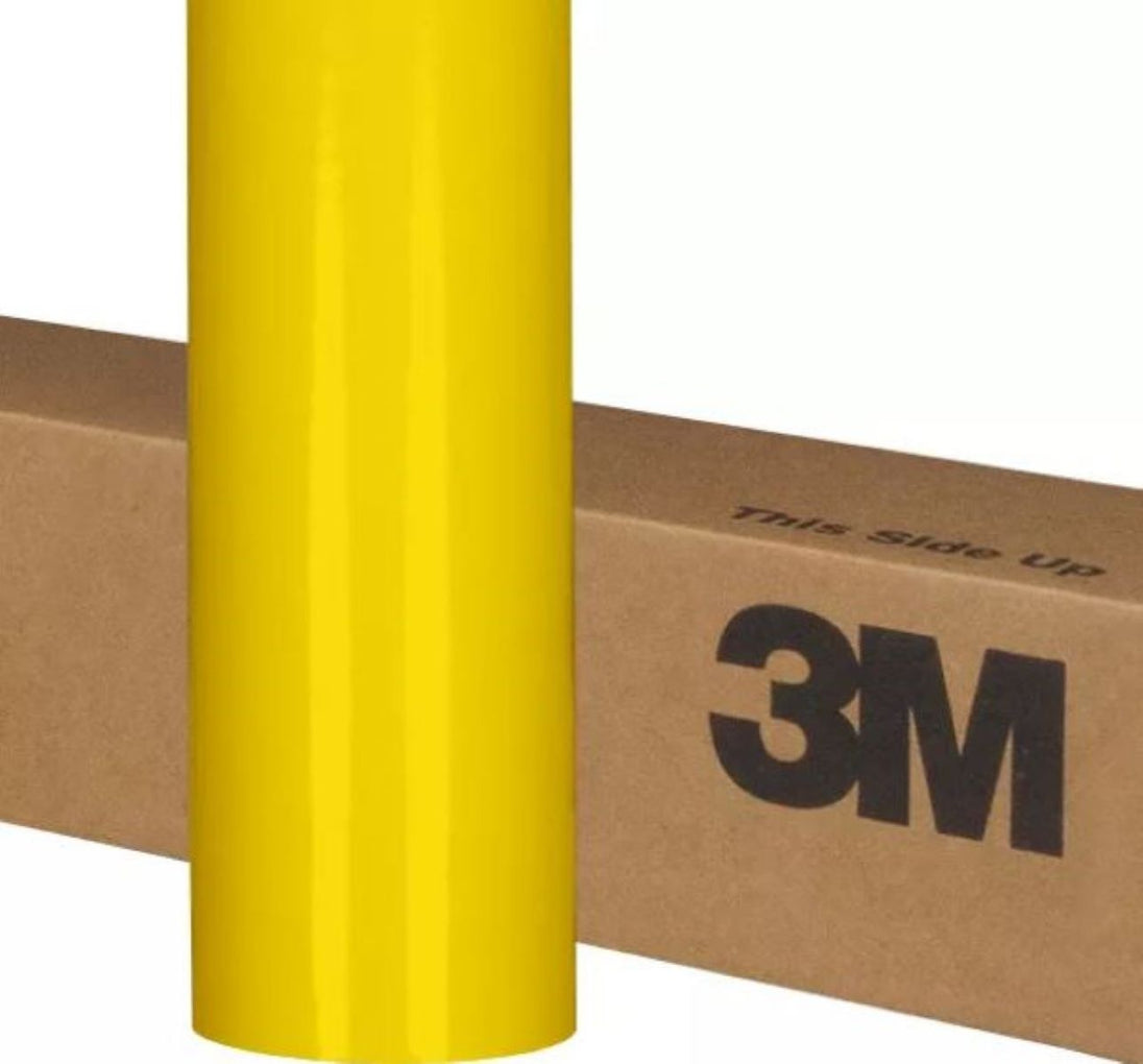 Yellow roll of 3M vinyl wrap on a cardboard box with 'This side up' text.