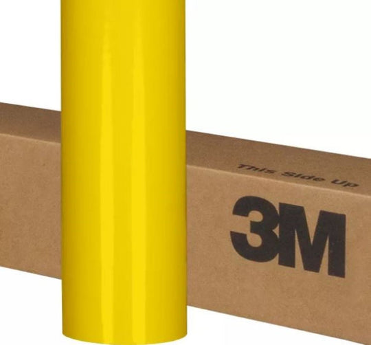 Yellow roll of 3M vinyl wrap on a cardboard box with 'This side up' text.