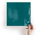 Hand holding a teal-colored square object against a white background