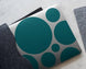 Notebook with teal circular patterns on a gray surface