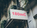 Building facade with a sign displaying '180mC' in red text.