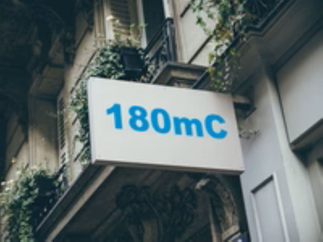 Building facade with a sign displaying '180mC' in blue text.