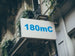 Building facade with a sign displaying '180mC' in blue text.