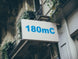 Building facade with a sign displaying '180mC' in blue text.