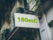 Building facade with a sign displaying '180mC' in green text.