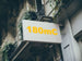 Building facade with a sign displaying '180mC' in yellow text.