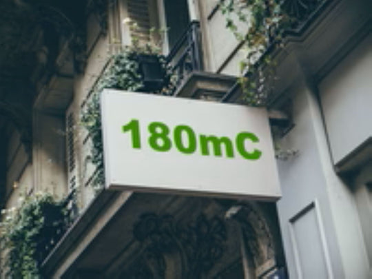 Building facade with a sign displaying '180mC' in green text.