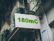 Building facade with a sign displaying '180mC' in green text.