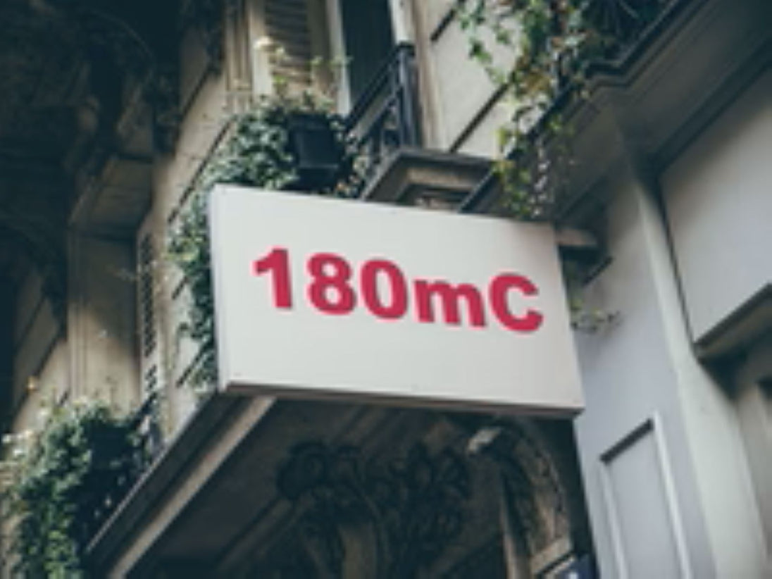 Building facade with a sign displaying '180mC' in red text.