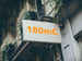 Building facade with a sign displaying '180mC' in orange text.