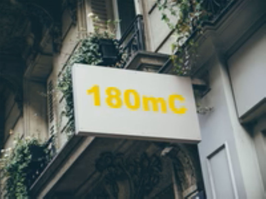 Building facade with a sign displaying '180mC' in yellow text.