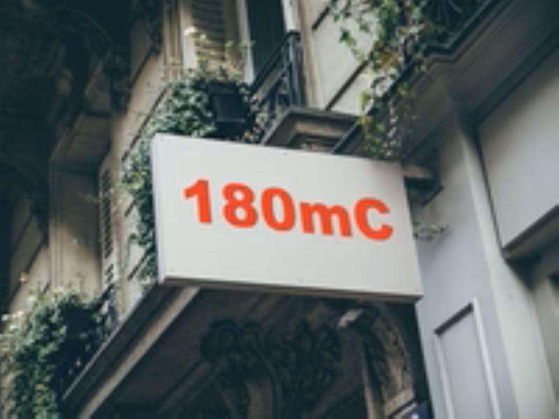 Building facade with a sign displaying '180mC' in red text.