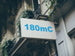 Building facade with a sign displaying '180mC' in blue text.