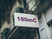 Building facade with a sign displaying '180mC' in purple text.