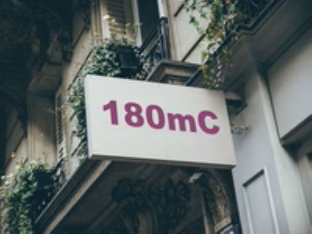 Building facade with a sign displaying '180mC' in pink text.