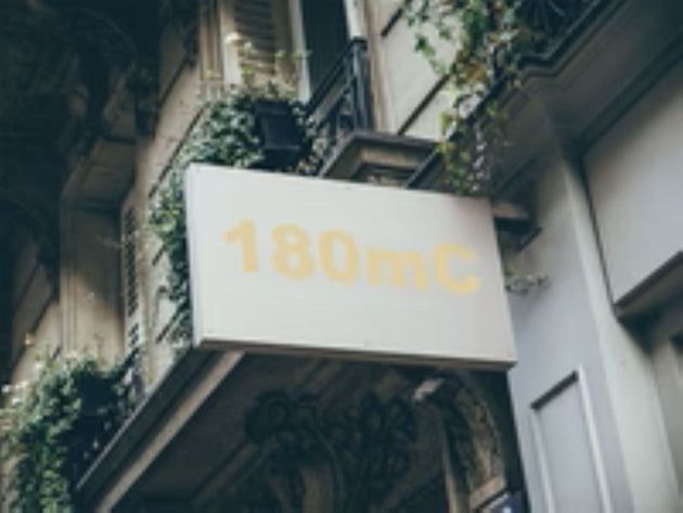 Building facade with a sign displaying '180mC' in gold lettering.