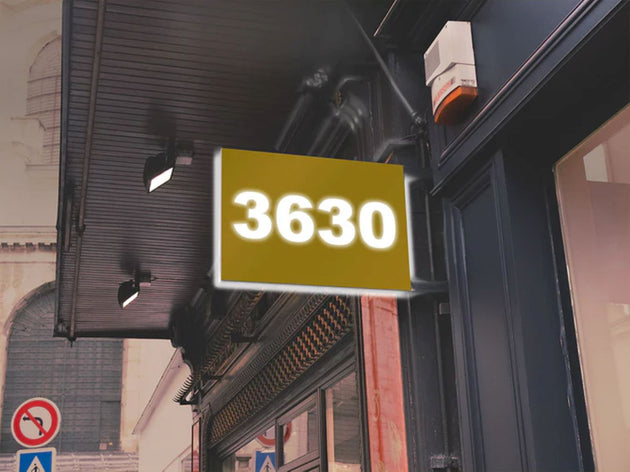 Street sign with the number 3630 on a building facade.