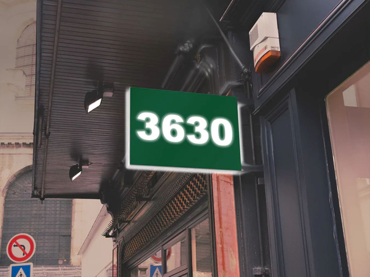 Green sign with the number 3630 on a building facade.