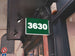Green sign with the number 3630 on a building facade.