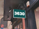 Green sign with the number 3630 on a building facade.
