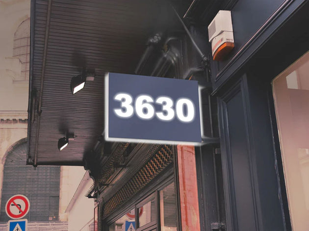 Street sign with the number 3630 on a building facade.