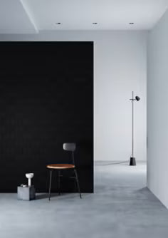 Minimalist interior with a black wall, white floor, and a single chair.