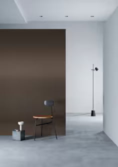 Modern interior with a chair against a brown wall and a light fixture on a white wall.