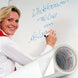 Woman writing on a whiteboard with a roll of whiteboard paper in the foreground.