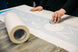 Person working with a roll of paper and a tool on a table with a design layout.