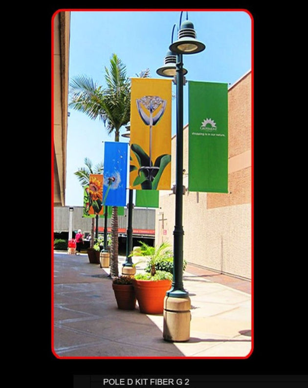 Colorful banners on a lamp post with potted plants and palm trees in the background.