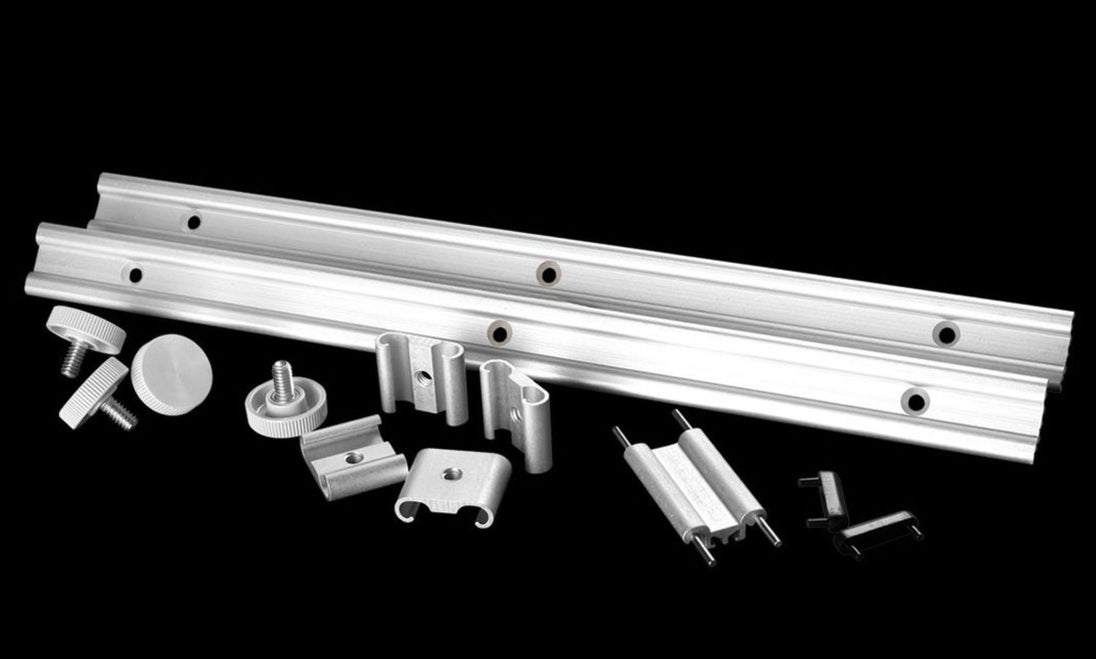 Metal components including a long metal bar and various smaller parts on a black background