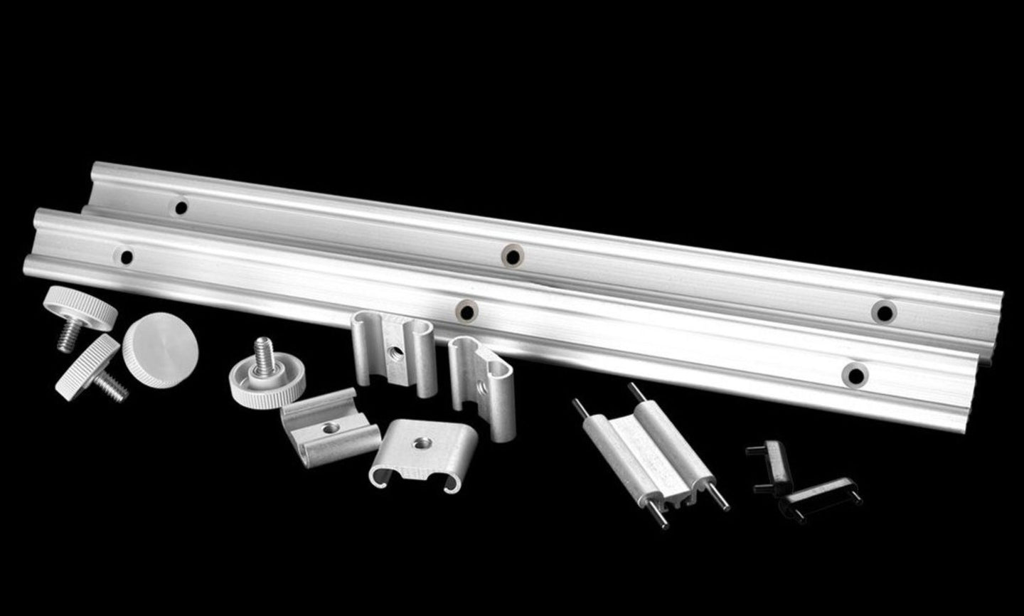Metal components including a long metal bar and various smaller parts on a black background