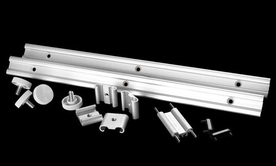 Metal components including a long metal bar and various smaller parts on a black background