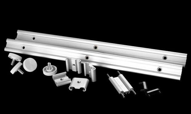 Metal components including a long metal bar and various smaller parts on a black background