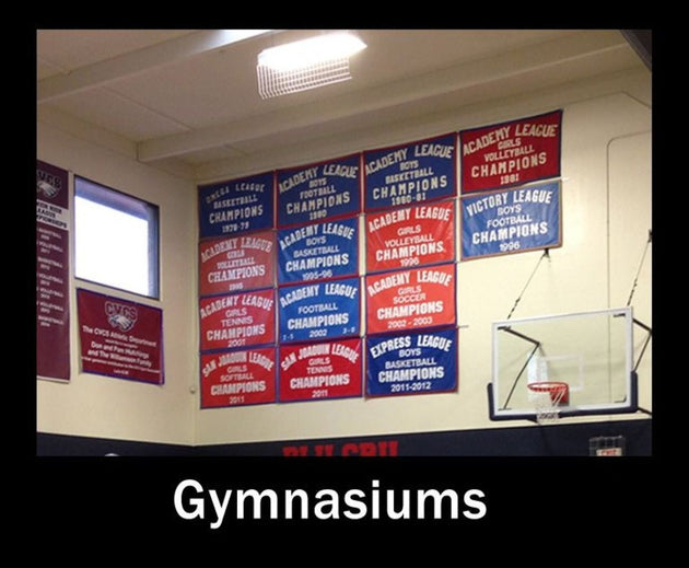 Gymnasium wall with sports championship banners and basketball hoop.