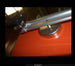 Close-up of a metal rod and clamp on an orange surface with a blurred background