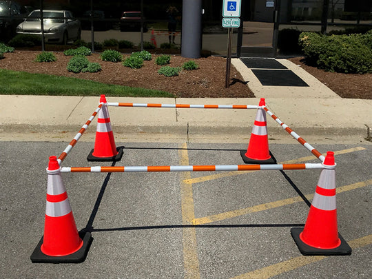 Orange traffic cones with white stripes set up in a parking lot.
