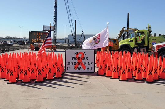 Safety cones with black ribbons and a warning sign at a construction site.