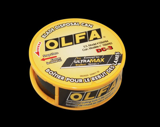Yellow Olfa blade disposal can on a black background