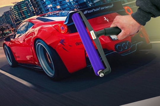 Red sports car with a hand holding a purple and black tool, set against an urban background.