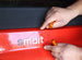 Person using a tool on a red vehicle with 'smart' branding.