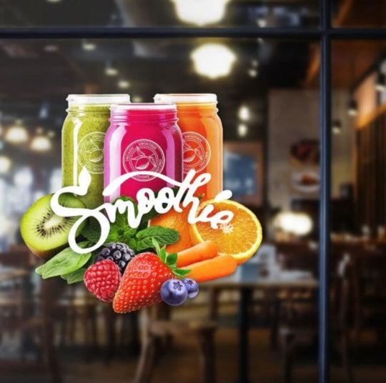 Three colorful smoothie jars with fruits and a blurred restaurant interior.