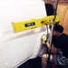 Person using a yellow car door impactor tool on a white car