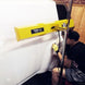 Person using a yellow car door impactor tool on a white car