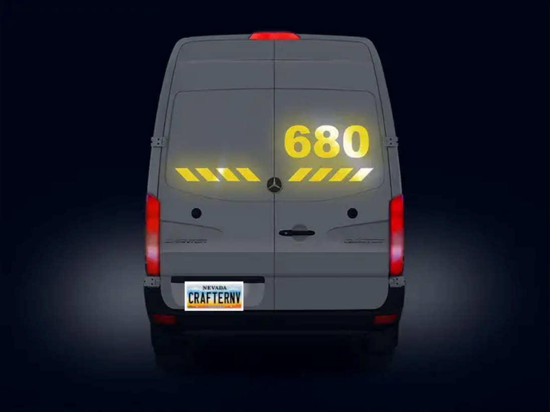 Back view of a van with digital display and license plate on a dark background
