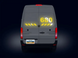 Back view of a van with digital display and license plate on a dark background