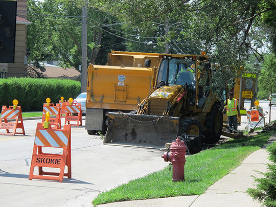 Construction vehicle on a residential street with safety cones and a fire hydrant.