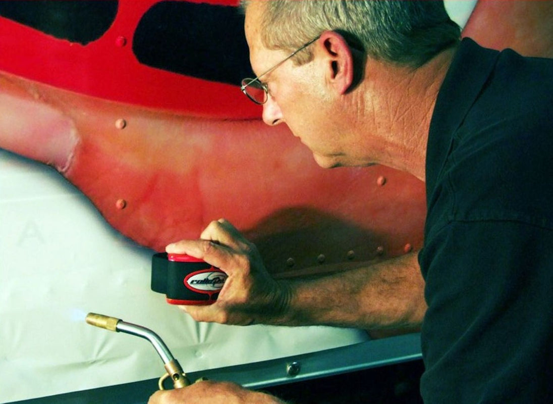 Person using a torch to work on a red vehicle panel